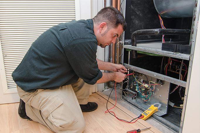 HVAC technician repairing and maintaining HVAC unit