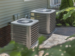 Two residential AC units outside of a house